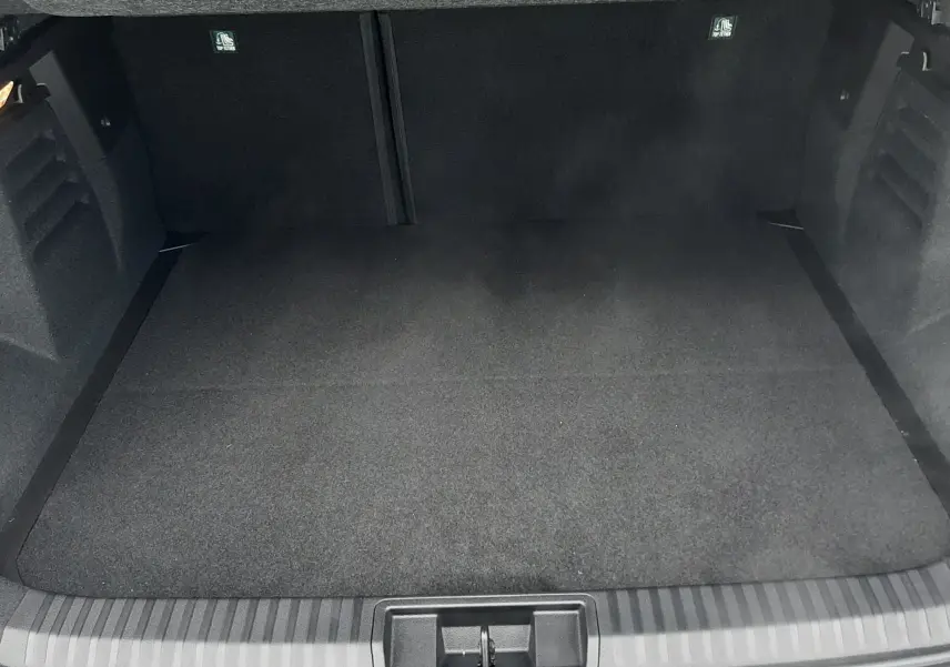 Vue plongeante sur le coffre vide d’une Renault Symbioz blanc nacré, soulignant son espace de rangement.