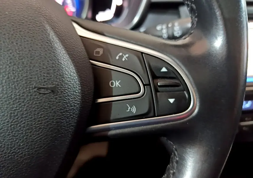 Gros plan sur les commandes multifonctions du volant cuir du Renault Kadjar Intens noir, avec boutons de navigation et téléphone.