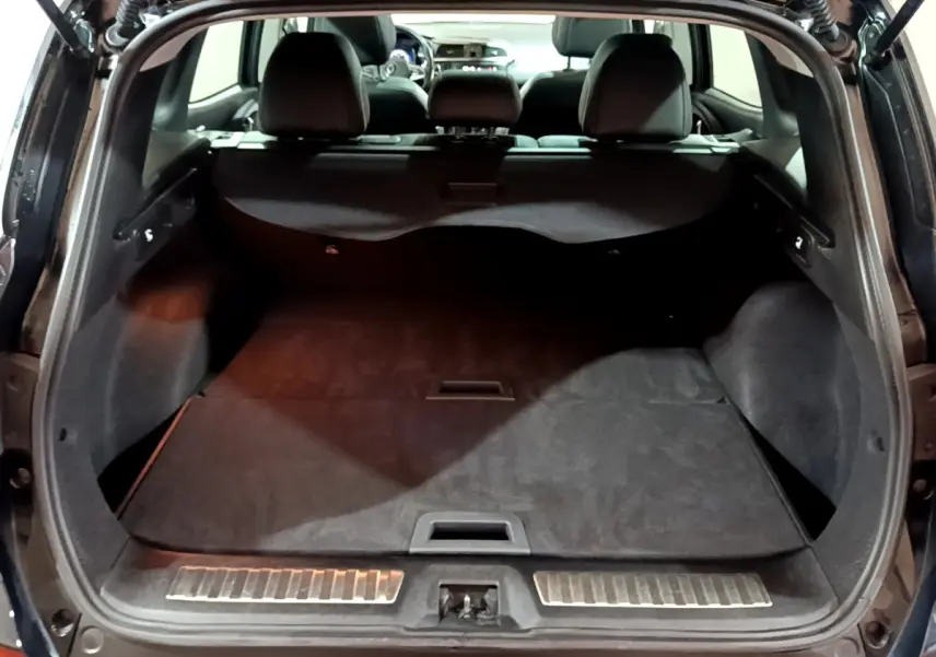 Coffre ouvert du Renault Kadjar Intens noir, vue arrière montrant l'espace de chargement et la banquette rabattue.