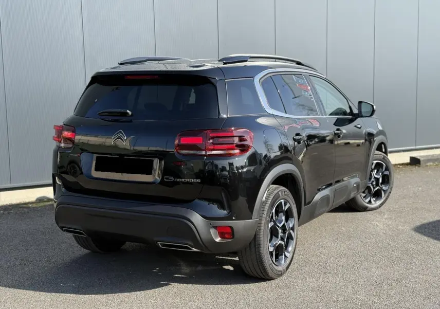Vue 3/4 arrière droite du Citroën C5 Aircross noir Perla avec jantes alliage bi-ton et barres de toit noires.