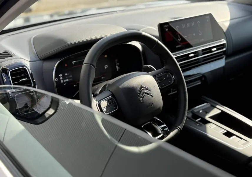 Vue intérieure côté conducteur du Citroën C5 Aircross 2025, volant cuir noir et tableau de bord numérique avec écran tactile.