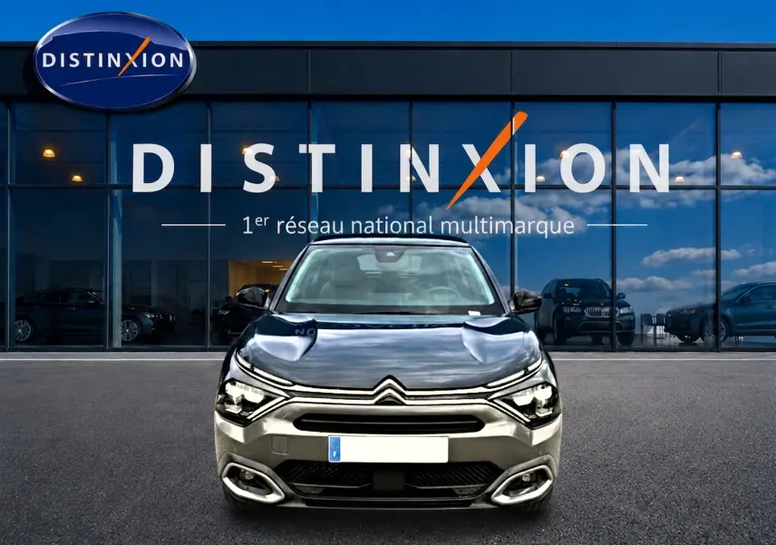 Citroën C4 1.5 BlueHDi 130 gris vue de face devant une vitrine avec logo Distinxion.
