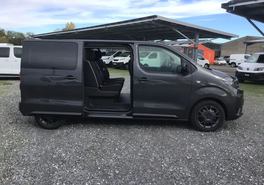 Vue latérale droite d'un Citroën Jumpy gris titane avec porte coulissante ouverte révélant les sièges passagers.