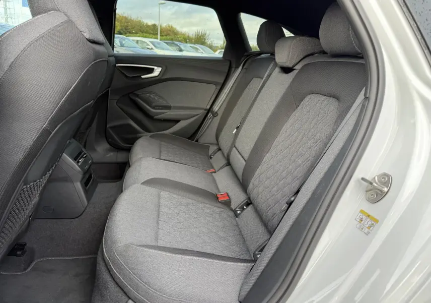 Vue côté droit des sièges arrière gris tissu de l'Audi A5 Avant blanc glacier métallisé 2025 avec porte ouverte.