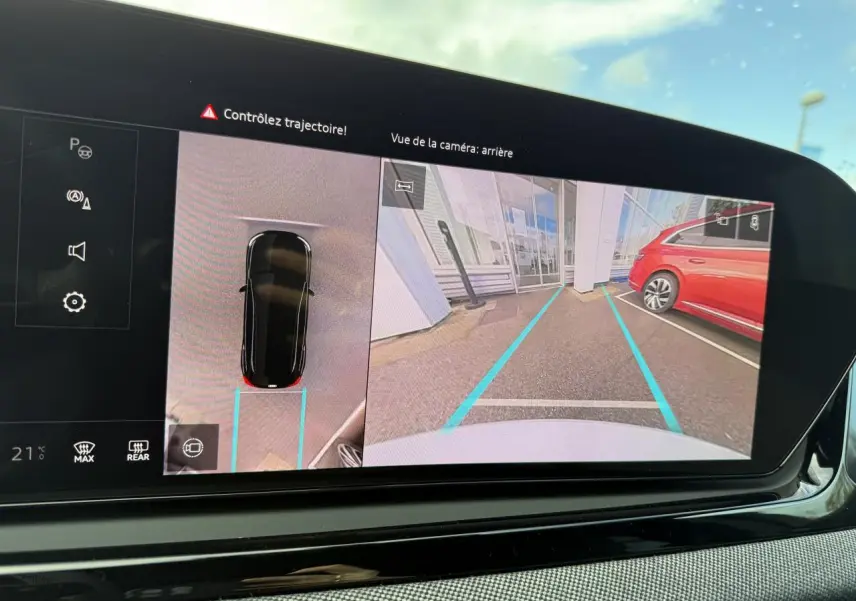 Vue de la caméra arrière sur l'écran du tableau de bord d'un Audi A5 blanc glacier, avec lignes de guidage bleues.