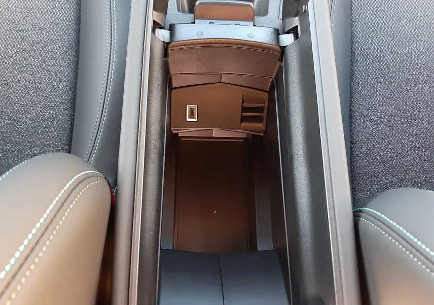 Vue plongeante sur le rangement central ouvert de la Peugeot 308 Bleu Obsession, avec sellerie noire et coutures contrastées.