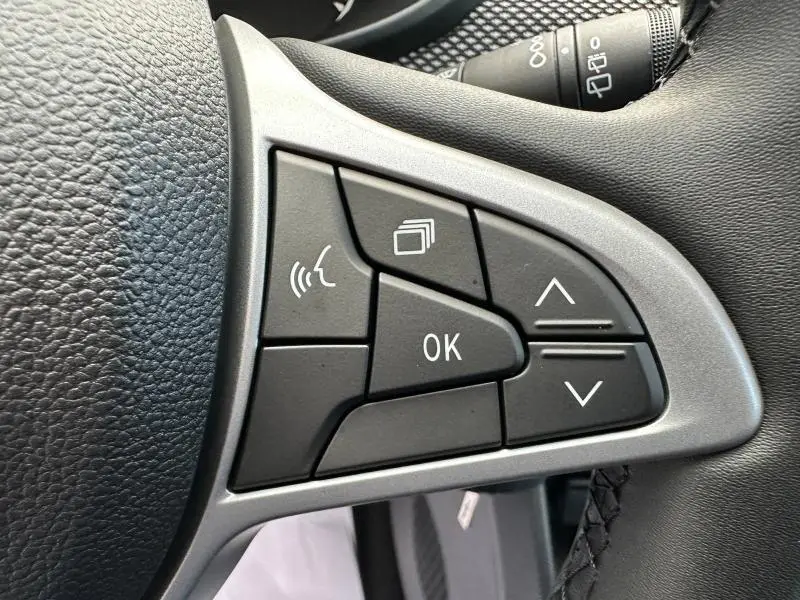 Gros plan sur les commandes au volant noir et gris du DACIA SANDERO blanc, version 1.0 TCe 90ch Stepway Expression 2025.