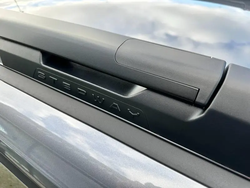 Gros plan sur l'inscription Stepway en relief sur la barre de toit noire d'une Dacia Sandero blanche.