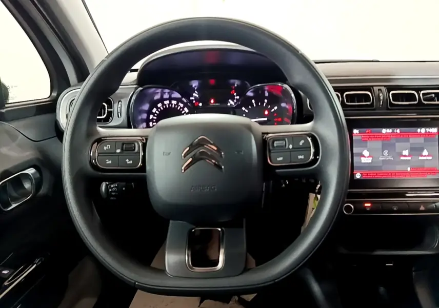 Vue frontale du tableau de bord et volant noir de la Citroën C3 PureTech 83 Shine avec écran tactile et commandes intégrées.