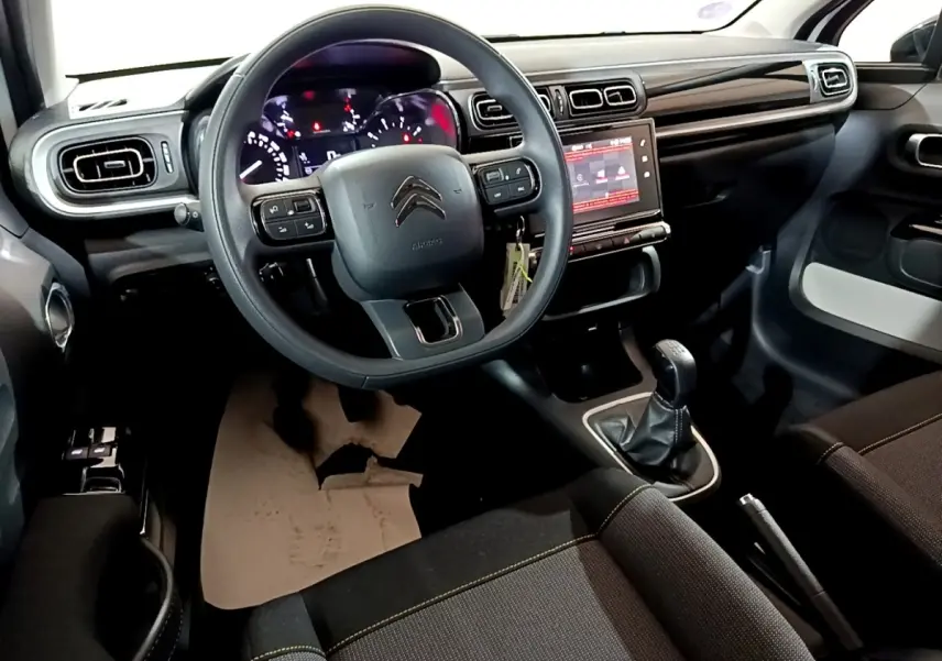 Vue intérieure avant de la Citroën C3 PureTech blanche 2023, tableau de bord avec écran tactile et volant multifonctions.