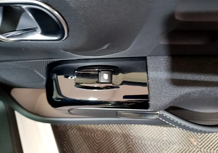 Commande de lève-vitre électrique côté gauche sur la porte intérieure noire d'une Citroën C3 blanche 2023.