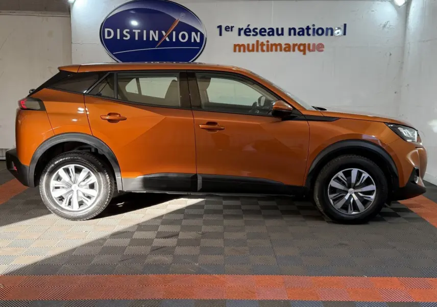 Vue de profil côté gauche d’un Peugeot 2008 orange 2022 avec jantes alliage et protections noires sur les bas de caisse.