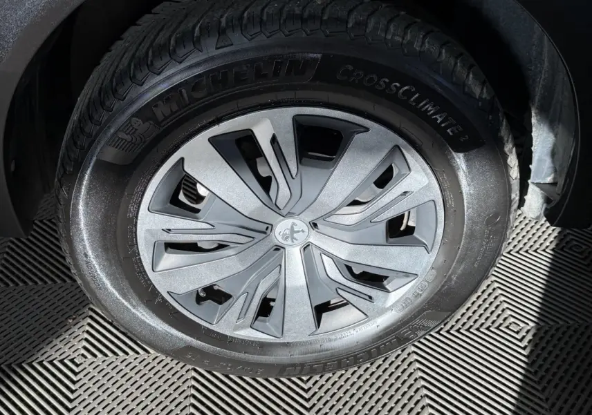 Gros plan sur la roue avant droite d’un Peugeot 2008 orange, avec jante argentée et pneu Michelin CrossClimate 2.