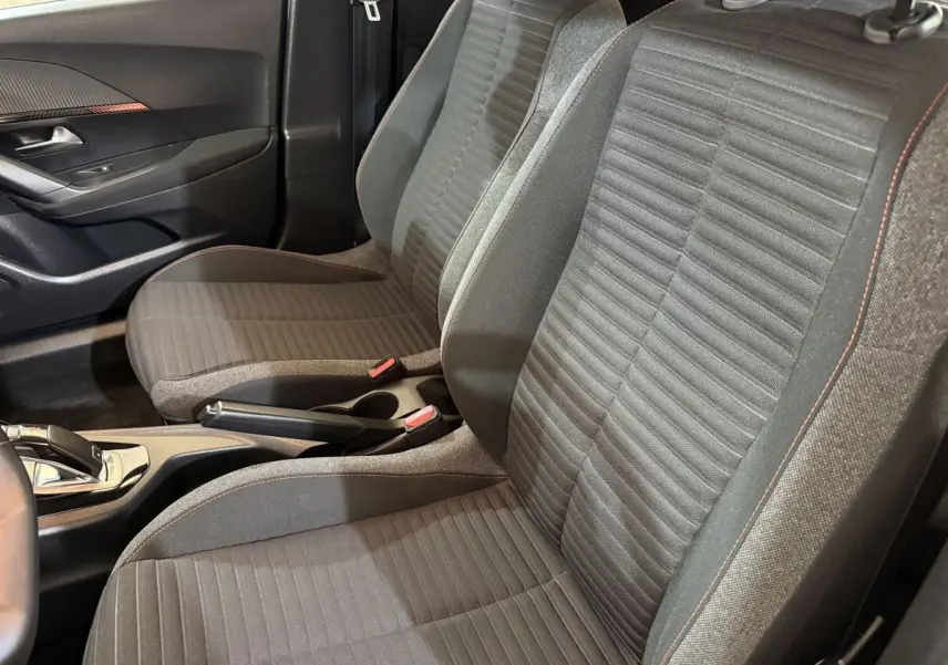 Vue rapprochée des sièges avant gris avec surpiqûres orange du Peugeot 2008, côté conducteur et console centrale visible.