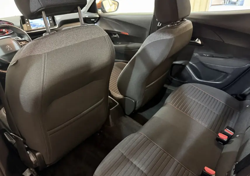 Vue intérieure arrière du Peugeot 2008 2022, sièges tissu noirs avec surpiqûres rouges et tableau de bord visible.