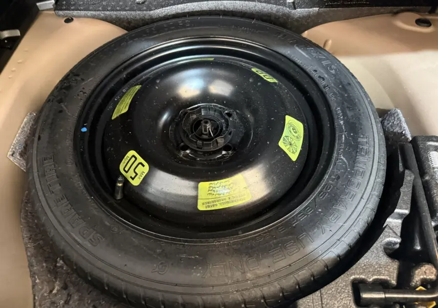 Gros plan sur la roue de secours noire dans le coffre d’un Peugeot 2008, version diesel orange 2022.