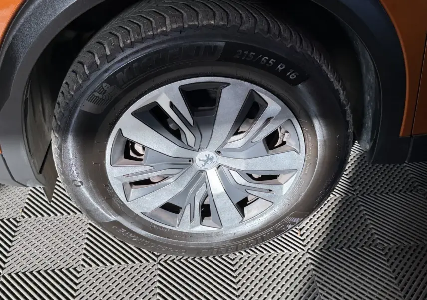Gros plan sur la roue avant droite du Peugeot 2008 orange, mettant en valeur la jante et le pneu Michelin.
