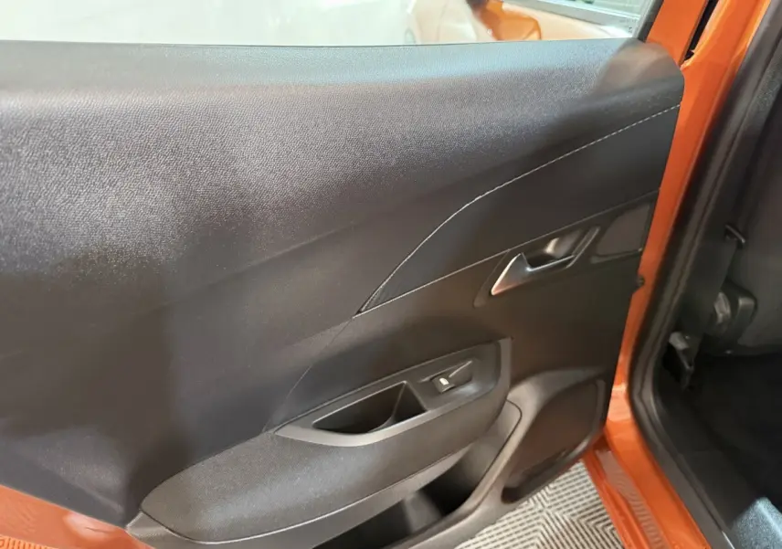 Vue intérieure côté gauche de la porte arrière orange du Peugeot 2008 avec poignée et commande de vitre électrique.