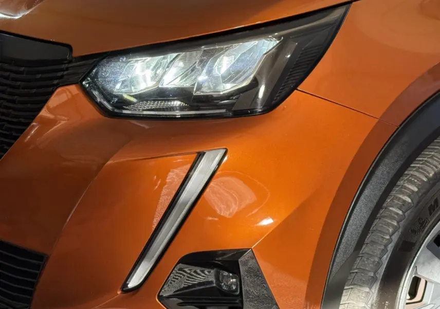 Gros plan sur l'avant droit orange du Peugeot 2008 2022, mettant en valeur le phare LED et le feu antibrouillard.