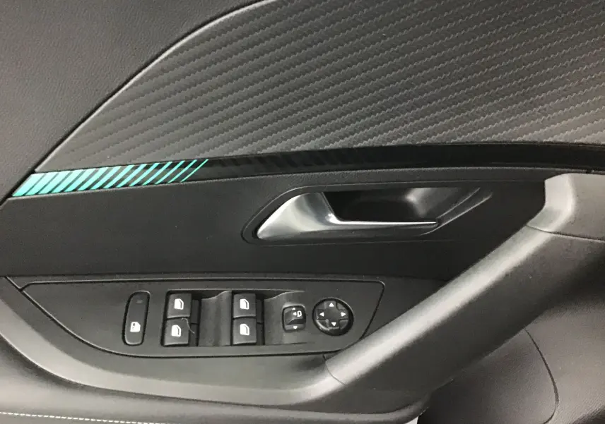 Poignée intérieure côté gauche de la Peugeot 2008 gris platinium, avec commandes de vitres et rétroviseurs.