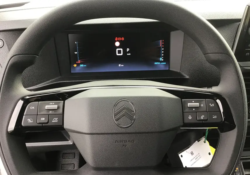 Vue rapprochée du volant noir du Citroën Jumpy cabine approfondie avec commandes intégrées et écran digital.