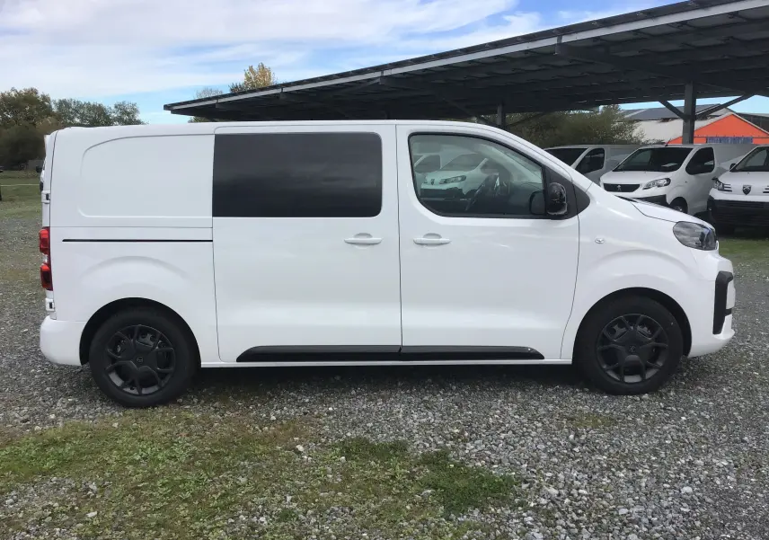 Vue de profil côté gauche d'un Citroën Jumpy cabine approfondie blanc avec vitres teintées et jantes noires.