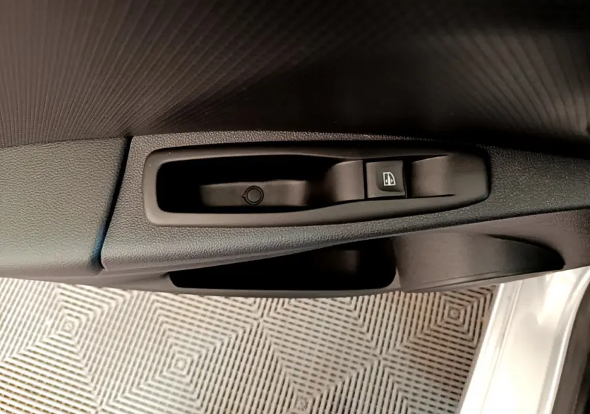 Gros plan sur la commande de lève-vitre côté conducteur d'une Renault Clio Business gris clair, intérieur noir.