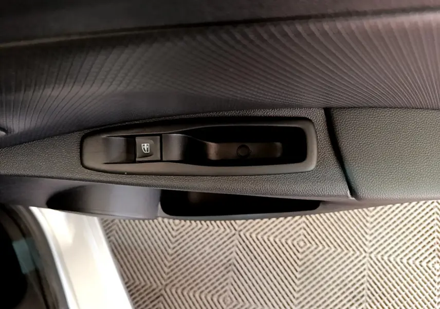 Gros plan sur la commande de lève-vitre côté conducteur de la Renault Clio Business TCe 90 gris clair de 2019.