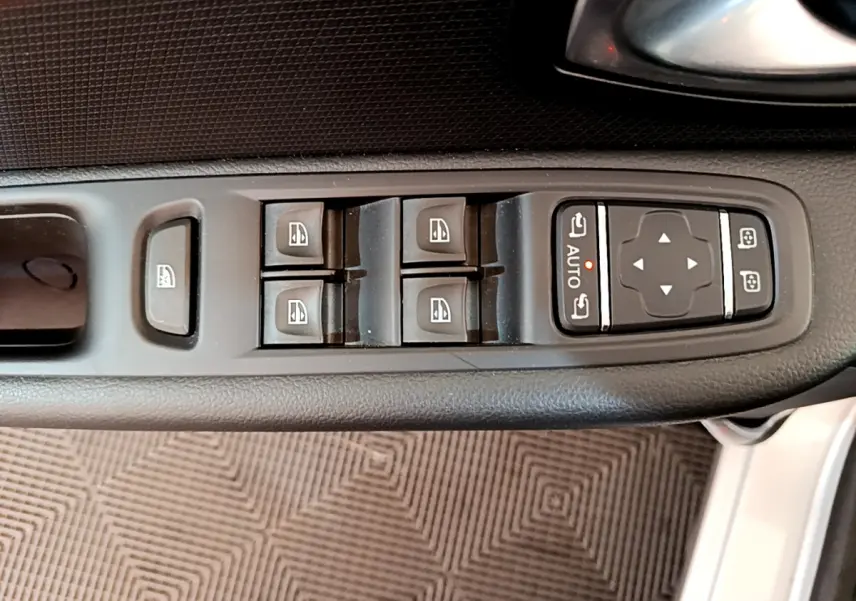 Gros plan sur les commandes des vitres et rétroviseurs côté conducteur d'une Renault Clio Business gris clair de 2019.