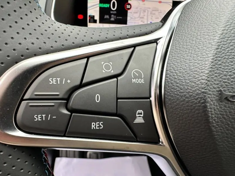 Gros plan sur les commandes noires du volant côté gauche du Renault Captur 2025 esprit Alpine, avec surpiqûres bleues visibles.