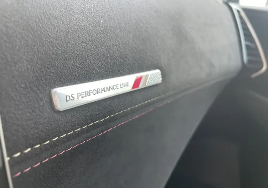 Gros plan sur l’inscription DS Performance Line sur la planche de bord en tissu gris noir du DS7 2021.