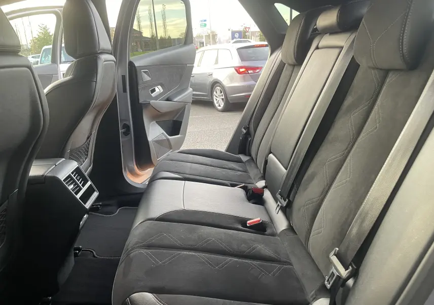 Vue intérieure arrière droite des sièges en cuir noir et alcantara du DS7 gris 2021 avec porte arrière ouverte.