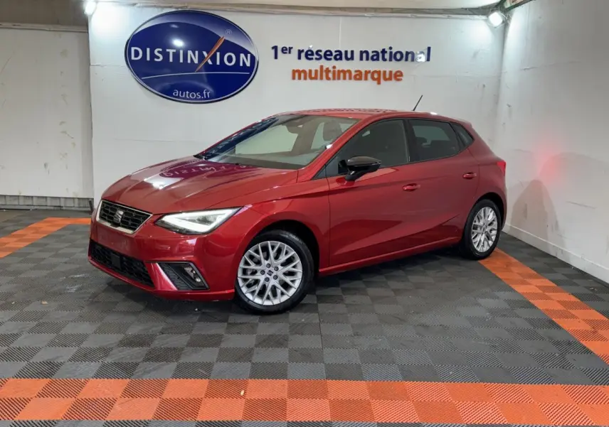 SEAT Ibiza 1.0 TSI 110 FR rouge vue 3/4 avant droit dans un showroom avec sol noir et orange.