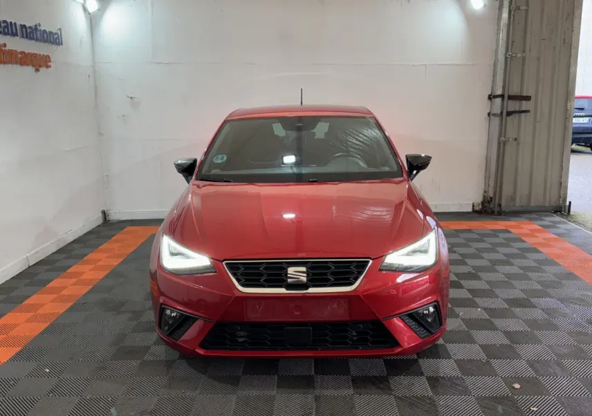 Vue frontale d'une SEAT Ibiza 1.0 TSI 110 FR rouge avec phares LED allumés dans un garage.