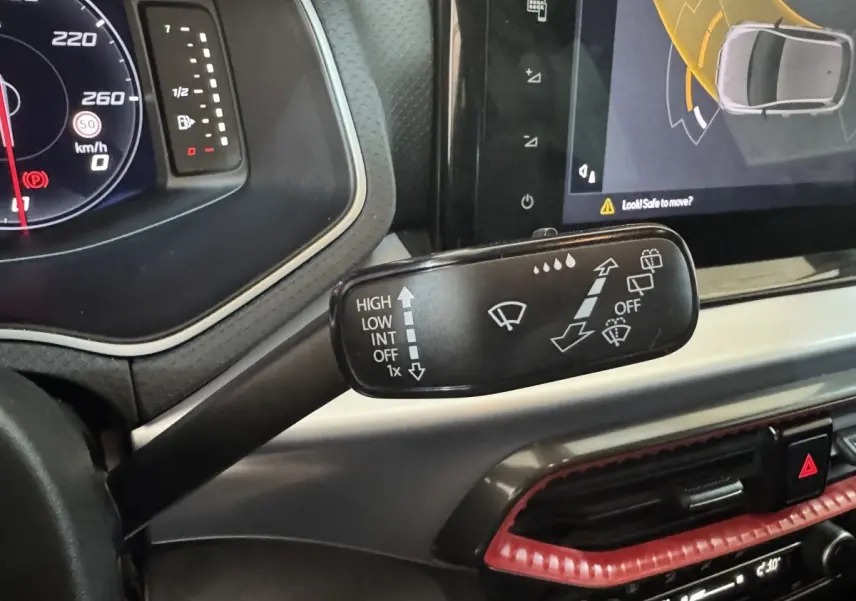 Le levier d'essuie-glace avec pictogrammes, tableau de bord numérique et écran tactile dans l'habitacle de la SEAT Ibiza rouge 2024.