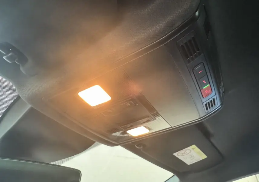 Plafonnier intérieur allumé avec commandes d'appel d'urgence dans un SEAT IBIZA 2024 rouge, vue vers le toit avant.