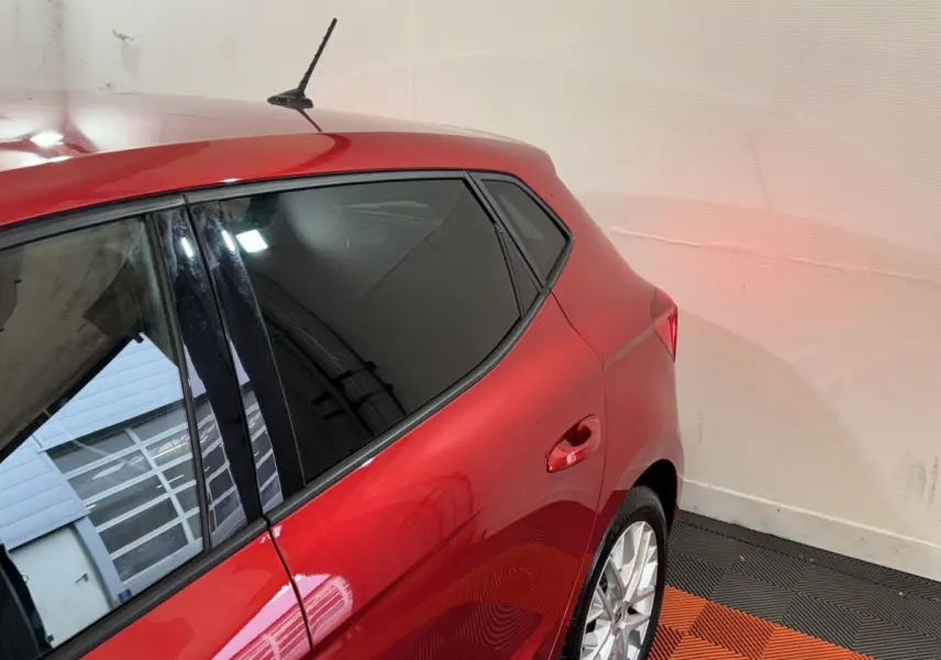 Vue 3/4 arrière droite d'une SEAT Ibiza 1.0 TSI 110 FR rouge avec vitres teintées et jantes alliage argentées.