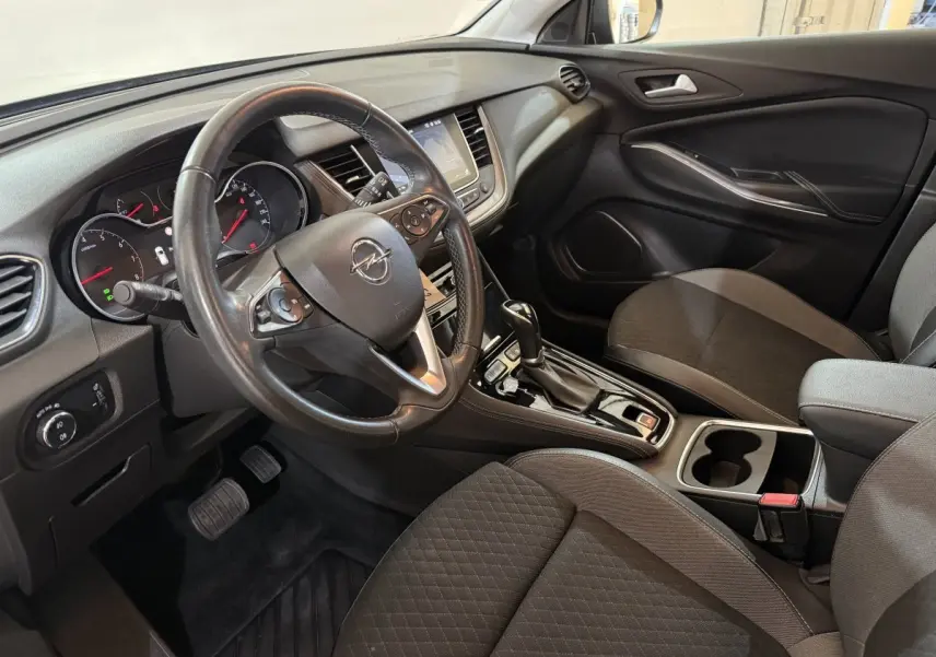 Intérieur avant droit de l’Opel Grandland X 2021, tableau de bord noir avec volant cuir et console centrale brillante.