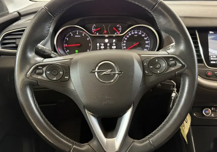 Vue rapprochée du volant en cuir noir de l'Opel Grandland X avec commandes intégrées et tableau de bord digital.