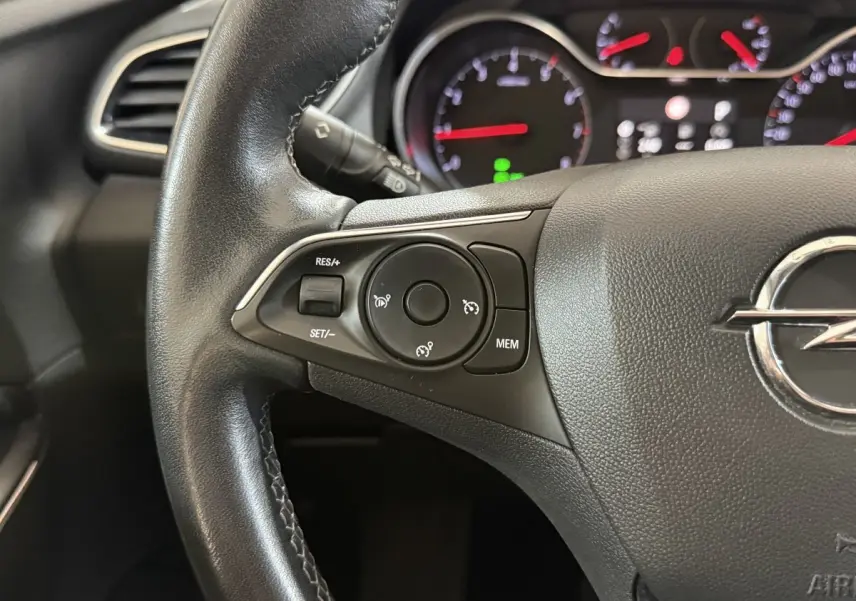 Gros plan sur le volant cuir noir de l'Opel Grandland X 2021 avec commandes de régulateur de vitesse et tableau de bord lumineux.