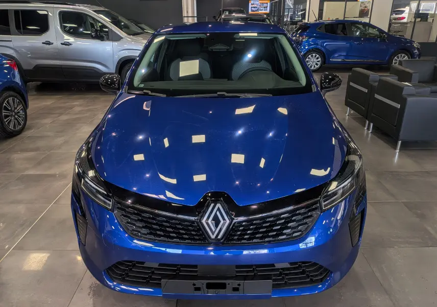 Vue avant d'une Renault Clio V Bleu Iron 2025, mettant en valeur sa calandre noire et ses phares LED fins.