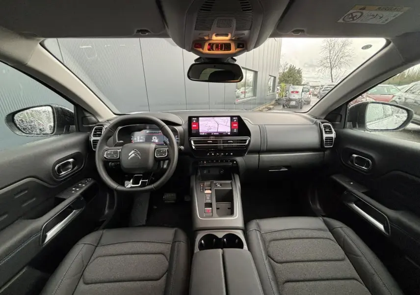 Vue intérieure avant du Citroën C5 Aircross 2025, tableau de bord noir avec écran tactile et volant multifonction.