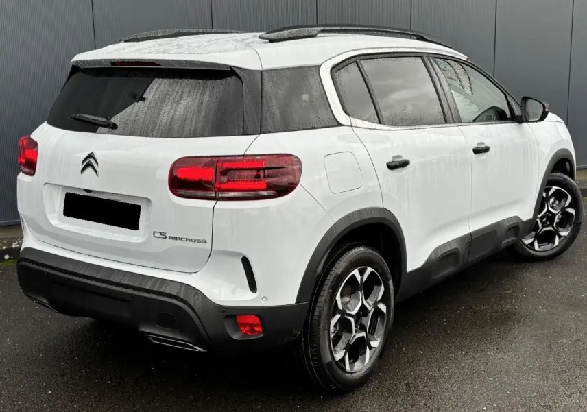 Vue 3/4 arrière droite d’un Citroën C5 Aircross blanc Okénite avec jantes alliage bi-ton et vitres surteintées.