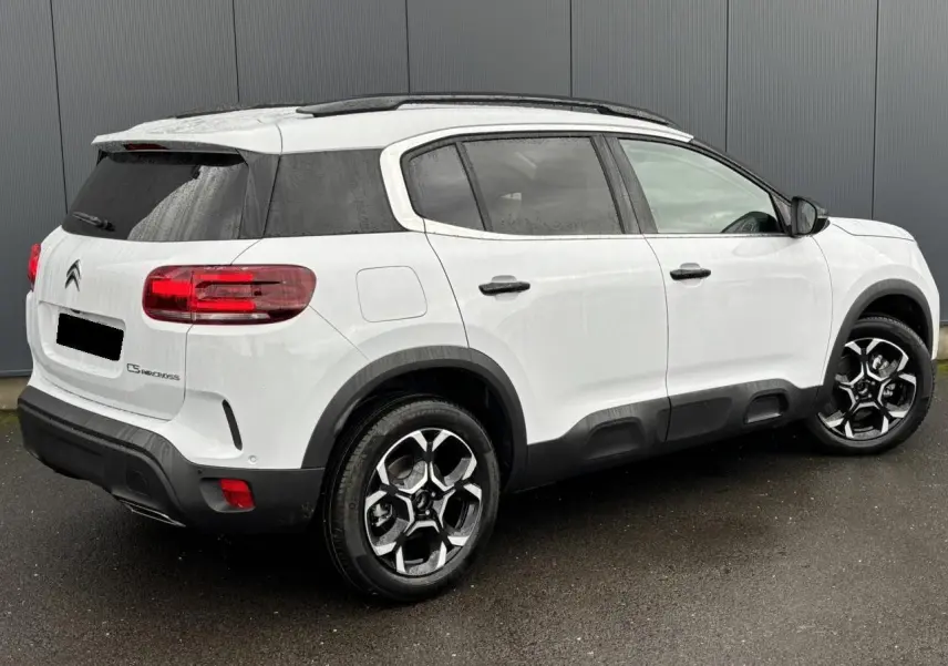 Vue 3/4 arrière droite d'un Citroën C5 Aircross blanc Okénite avec jantes alliage bi-ton et vitres surteintées.