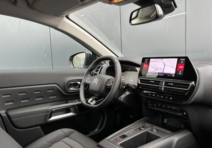 Vue intérieure côté conducteur du Citroën C5 Aircross 2025 avec tableau de bord noir et écran tactile central.