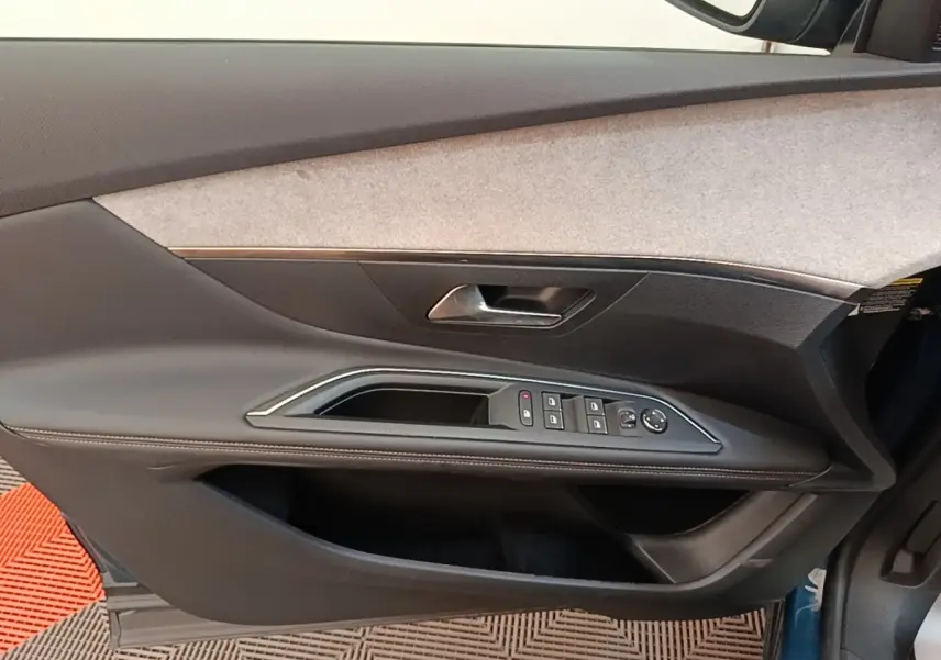 Vue intérieure côté gauche de la porte avant d'un Peugeot 3008 bleu avec commandes de vitres et poignée intégrée.