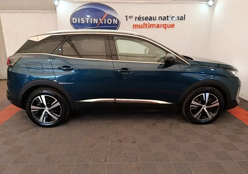 Profil latéral gauche d’un Peugeot 3008 hybride rechargeable bleu avec jantes alliage et toit blanc en showroom.