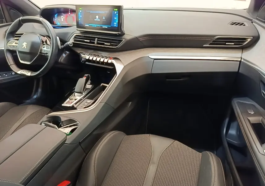Intérieur Peugeot 3008 hybride 2022 vu côté passager, tableau de bord moderne avec écran tactile central et volant compact.