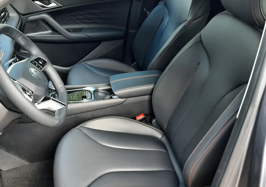 Vue intérieure côté conducteur du MG MOTOR EHS 1.5 HYBRID+ 224CH Luxury 2026, sièges cuir noir avec surpiqûres contrastées.