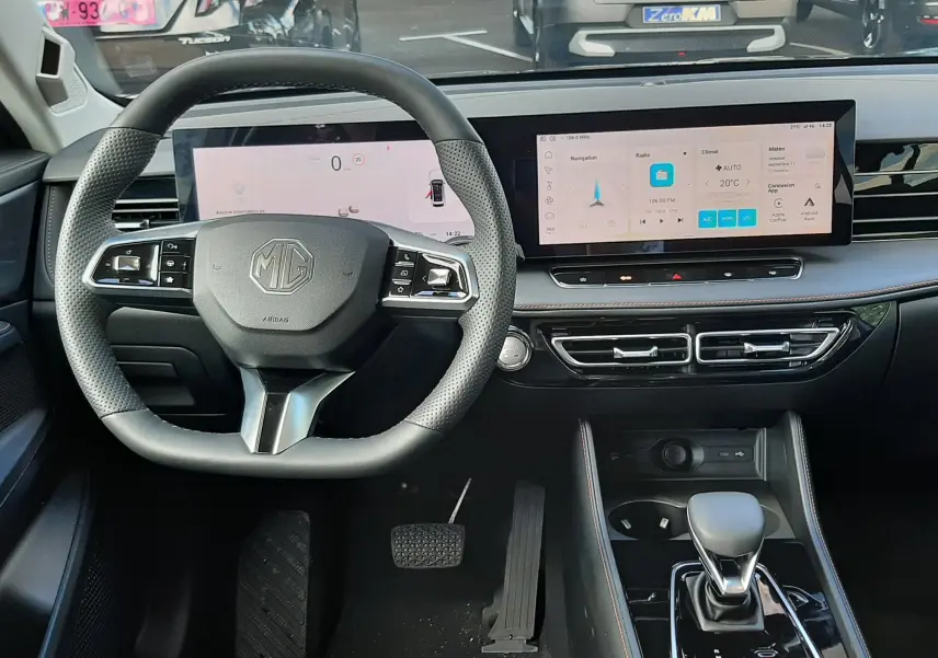 Vue intérieure centrée sur le volant et le tableau de bord numérique du MG MOTOR EHS Camden Grey, avec écran tactile large.